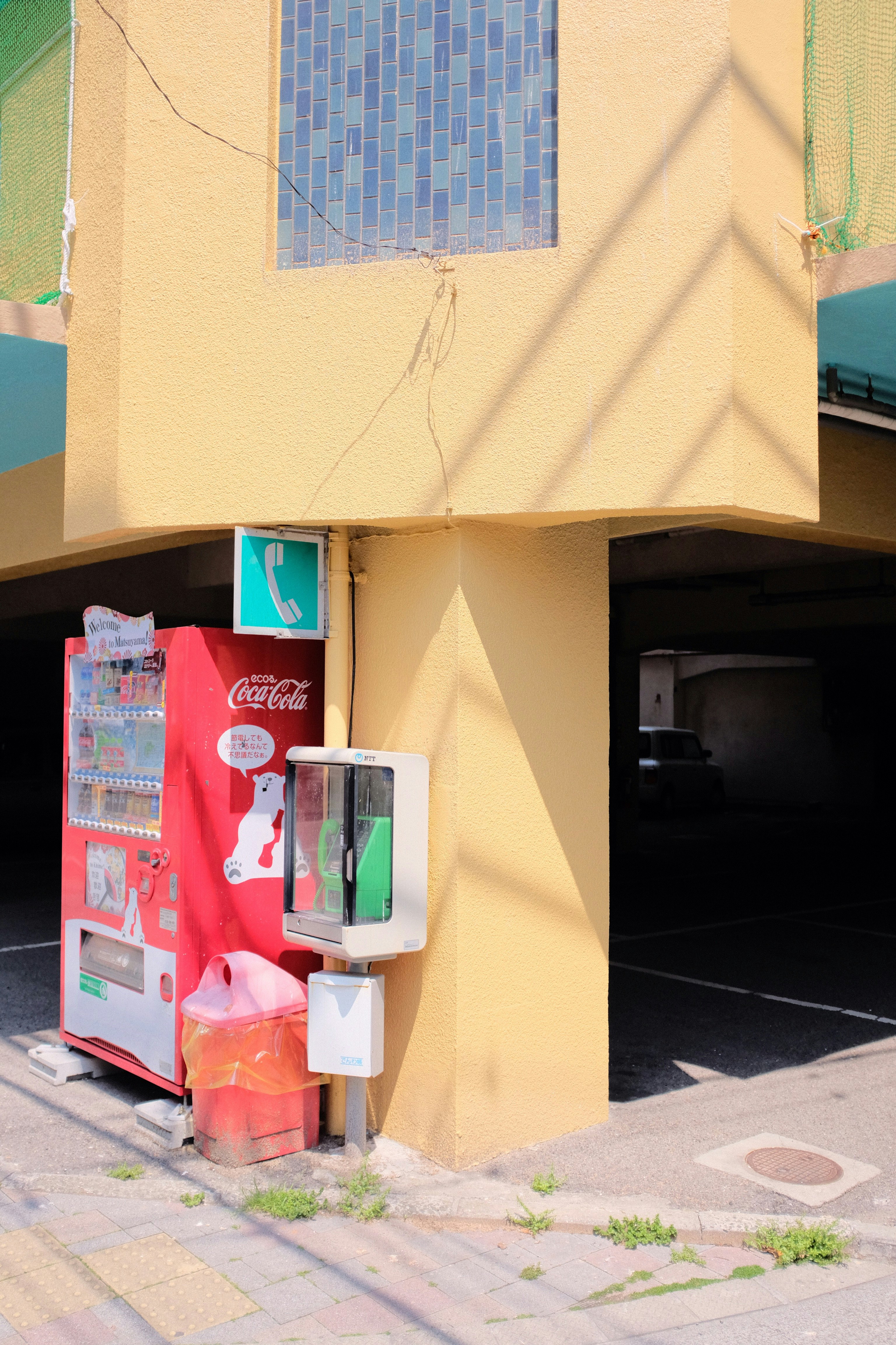 red and white plastic trash bin beside yellow concrete building